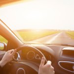 driving car, hands of driver on steering wheel, travel background